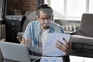 Annoyed frustrated entrepreneur looking at paper report with bad news