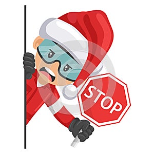 Annoyed industrial mechanical worker with Santa Claus hat peeking out from behind a wall holding stop sign. Merry christmas.