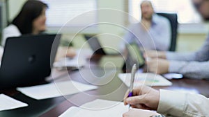 Annoyed man drumming pen on table, showing disagreement with colleagues opinion