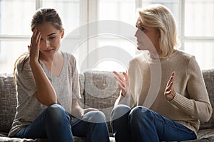 Annoyed mature retired mother telling complaints to daughter.