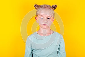 Annoyed, sad, upset kids emotion. Cute upset little girl standing isolated over yellow background