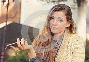 Annoyed sad woman with mobile phone standing outside in the street