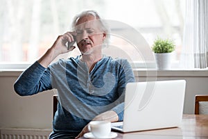 Annoyed aged man having unpleasant phone talk photo