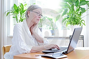 Annoyed senior woman laptop calculator