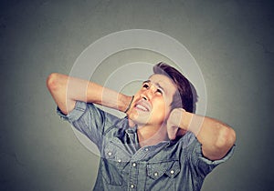 Annoyed stressed man covering his ears looking up