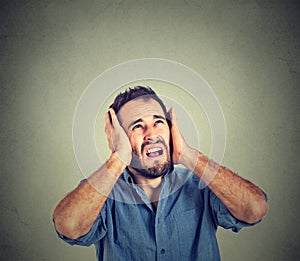 Annoyed, stressed man covering his ears, looking up, stop making loud noise photo