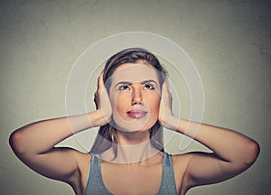 Annoyed, unhappy, stressed woman covering her ears, looking up