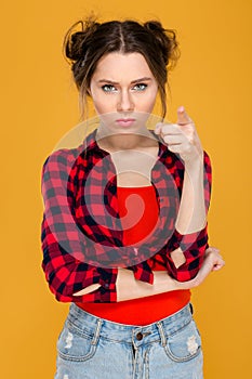 Annoyed unpleased young woman standing and pointing on camera