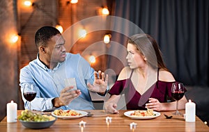Annoyed Woman Arguing With Boyfriend In Restaurant, Blaming Him For Smartphone Addiction