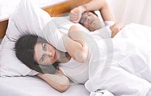 Annoyed woman hiding head from her snoring husband