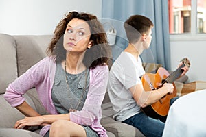 Annoyed woman sitting, son on background