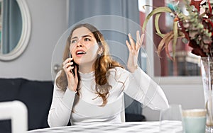 Annoyed woman talking on phone at home