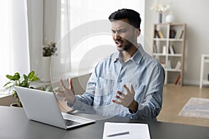 Annoyed worried young Indian business man having problems with laptop