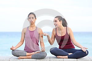 Annoyed yogi trying to do yoga with a friend disturbing