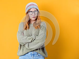 Annoyed young woman, isolated on yellow background. Displeased girl with arms crossed