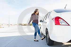 Annoyed young woman kicking her car`s flat tire