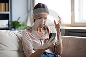 Annoyed young woman looking at mobile phone screen.