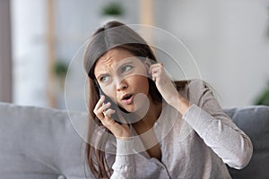 Annoyed young woman talking on phone not hearing bad signal