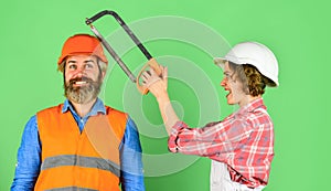 Annoying edits. Couple renovating home. Man and woman wear safety helmet. Home Renovation. She is sawing him. Hand Saw photo