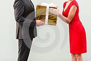 Anonym businessman give a present woman in red dress.