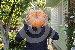 Anonym man holding a pumpkin in hands like a head.