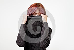 Anonymous concept. Young woman with interesting colorful hairstyle hiding her face with colar.