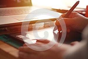 Anonymous designer working on laptop computer and pentablet graphic tablet, blurry silhouette