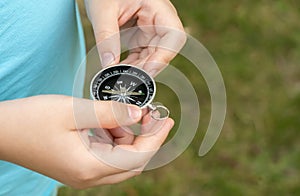 Anonymous elementary school age child holding a compass in hands, closeup, world directions, travel, journey, exploration symbol photo