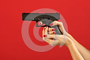 Anonymous female hand holding pistol on red backdrop