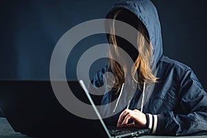 Anonymous girl hacker programmer uses laptop to hack system. Stealing personal data and infection of malicious virus.