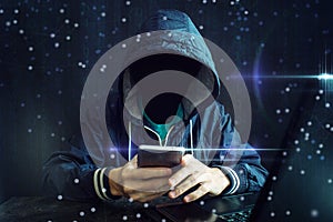 An anonymous hacker without a face uses a mobile phone to hack the system. The concept of cyber crime