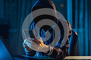 Anonymous hacker programmer uses a laptop to hack the system in the dark. Concept of cybercrime and hacking database