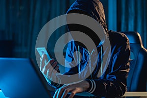 Anonymous hacker programmer uses a laptop to hack the system in the dark. Concept of cybercrime and hacking database