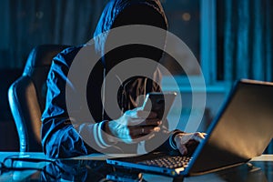 Anonymous hacker programmer uses a laptop to hack the system in the dark. Concept of cybercrime and hacking database