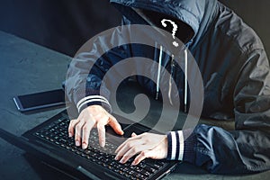 Anonymous hacker programmer uses a laptop to hack the system. St