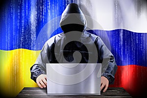 Anonymous hacker working on a laptop, flags of Ukraine and Russia