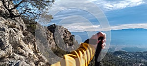 Anonymous male traveler with trekking pole standing on hill in highlands