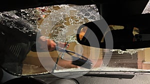 Anonymous man cleaning windshield wipers using automobile brush. Wiping off snow and ice from car and windscreen