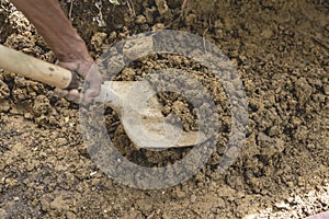 An anonymous man digging into the ground with a shovel, excavating a hole for a house foundation