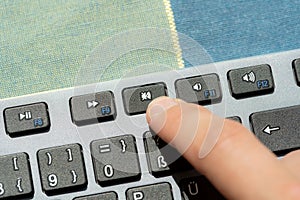 Anonymous man pressing the mute button, sound off key on a modern computer keyboard, hand, finger closeup, detail. Muting