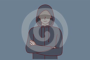 Anonymous man stands with arms crossed and hiding eyes behind hood for concept secret surveillance