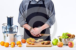Anonymous man wearing an apron, preparing fresh fruit juice using modern electric juicer, healthy lifestyle detox concept on white