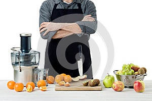 Anonymous man wearing an apron, preparing freshly made fruit juice, using modern electric juicer, healthy lifestyle concept