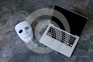Anonymous mask to hide identity on computer laptop - internet criminal and cyber security threat concept