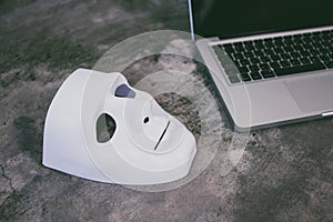 Anonymous mask to hide identity on computer laptop - internet criminal and cyber security threat concept