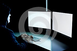Anonymous and masked hacker using computer with isolated white monitor screen to insert any text, word, pictures
