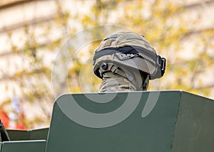 Anonymous military soldier in a camo camouflage uniform and a helmet sitting in an armored vehicle turret head closeup, back shot