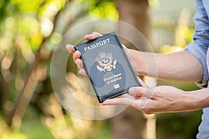 Anonymous unrecognizable man holding up, showing a USA passport, United States of America passport case, one person, hands closeup