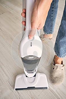 Anonymous woman removing container from modern upright vacuum cleaner