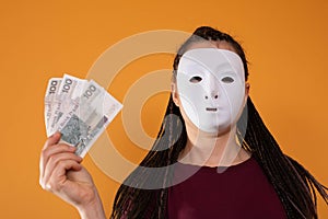 An anonymous woman stands and pulls her hand in with paper banknotes with the face value of one hundred Polish zlotys